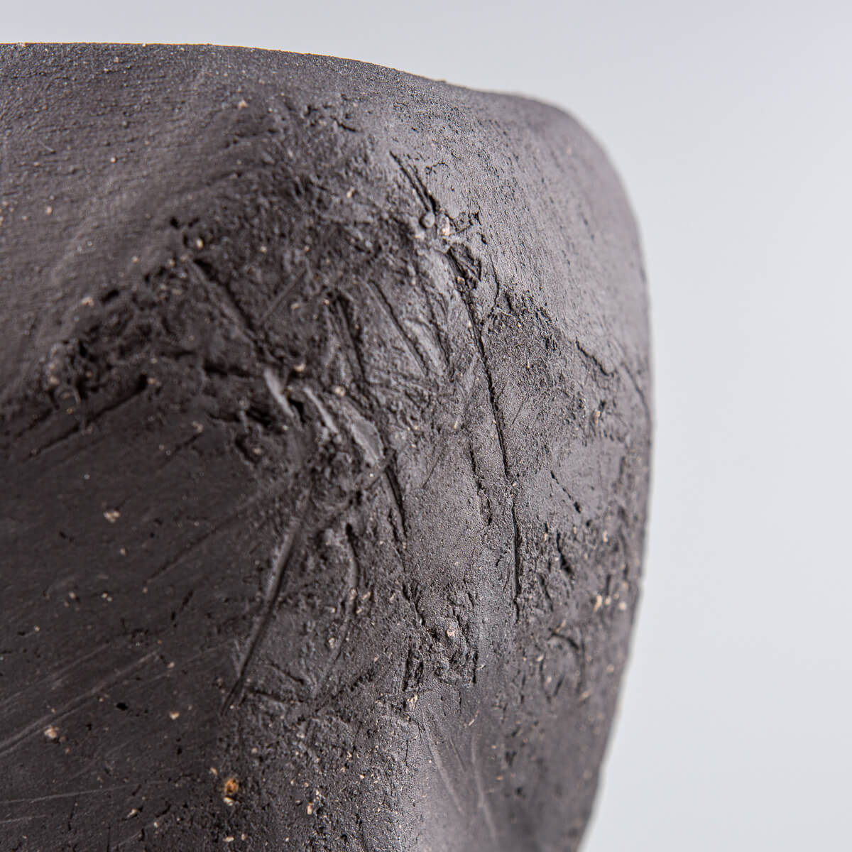 Luxury pottery vase with textured black clay surface and green glossy glaze.