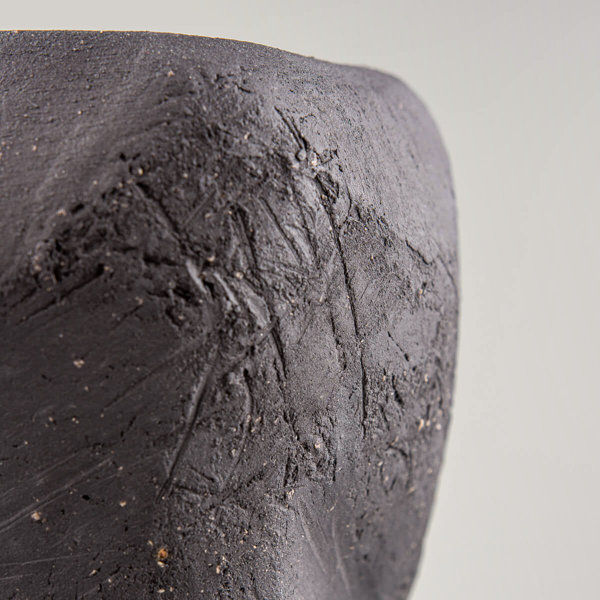 Luxury pottery vase with textured black clay surface and green glossy glaze.