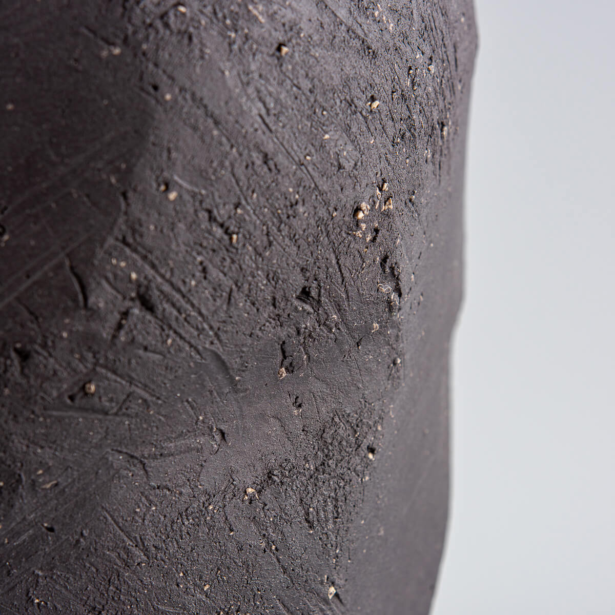 Rustic handmade pottery vase with organic black clay surface and glossy interior.