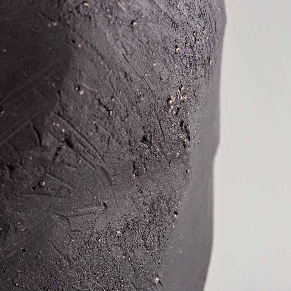 Rustic handmade pottery vase with organic black clay surface and glossy interior.