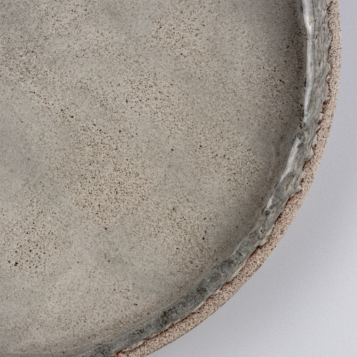 Angled view of handmade dinner plate highlighting straight edge and gray glaze.