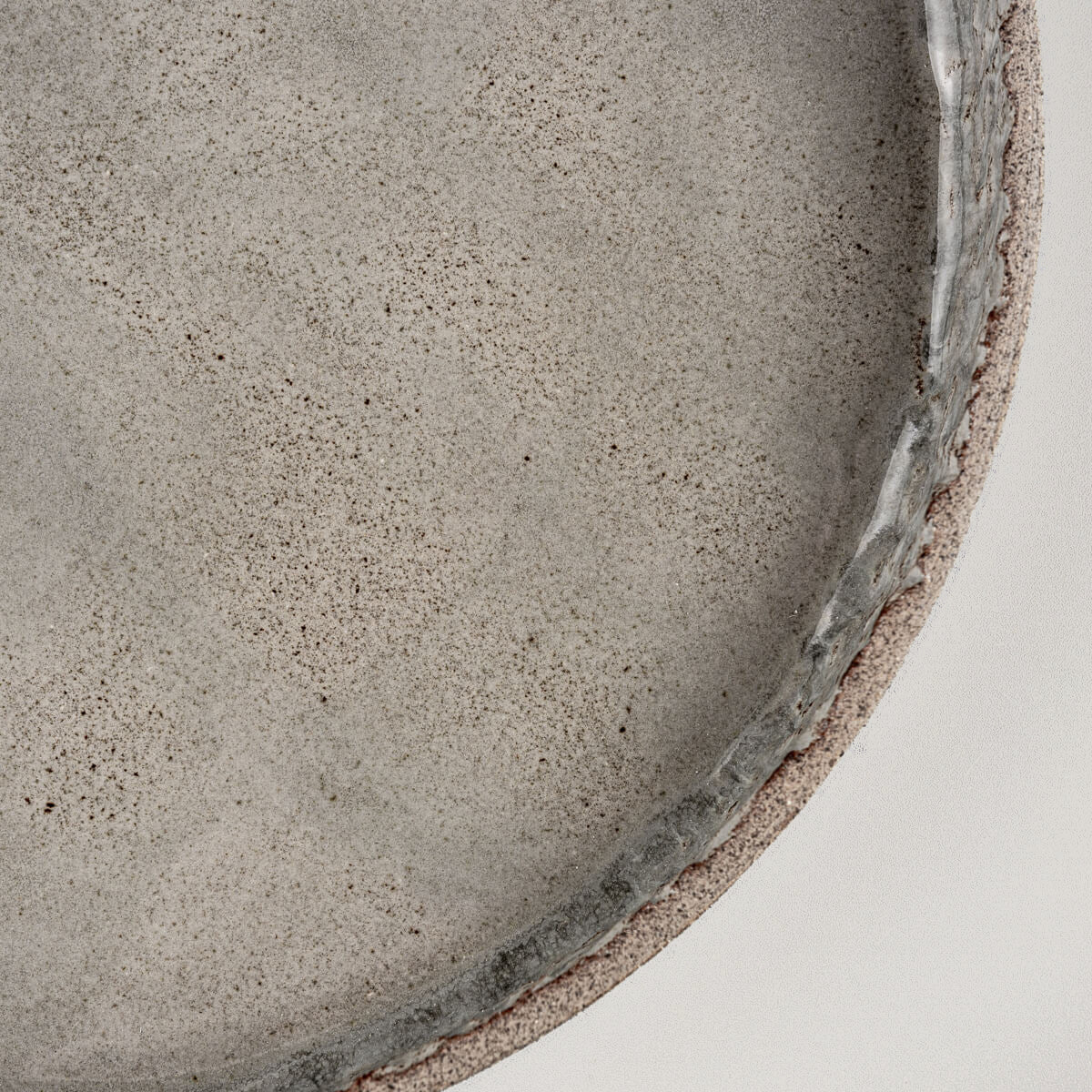 Angled view of handmade dinner plate highlighting straight edge and gray glaze.