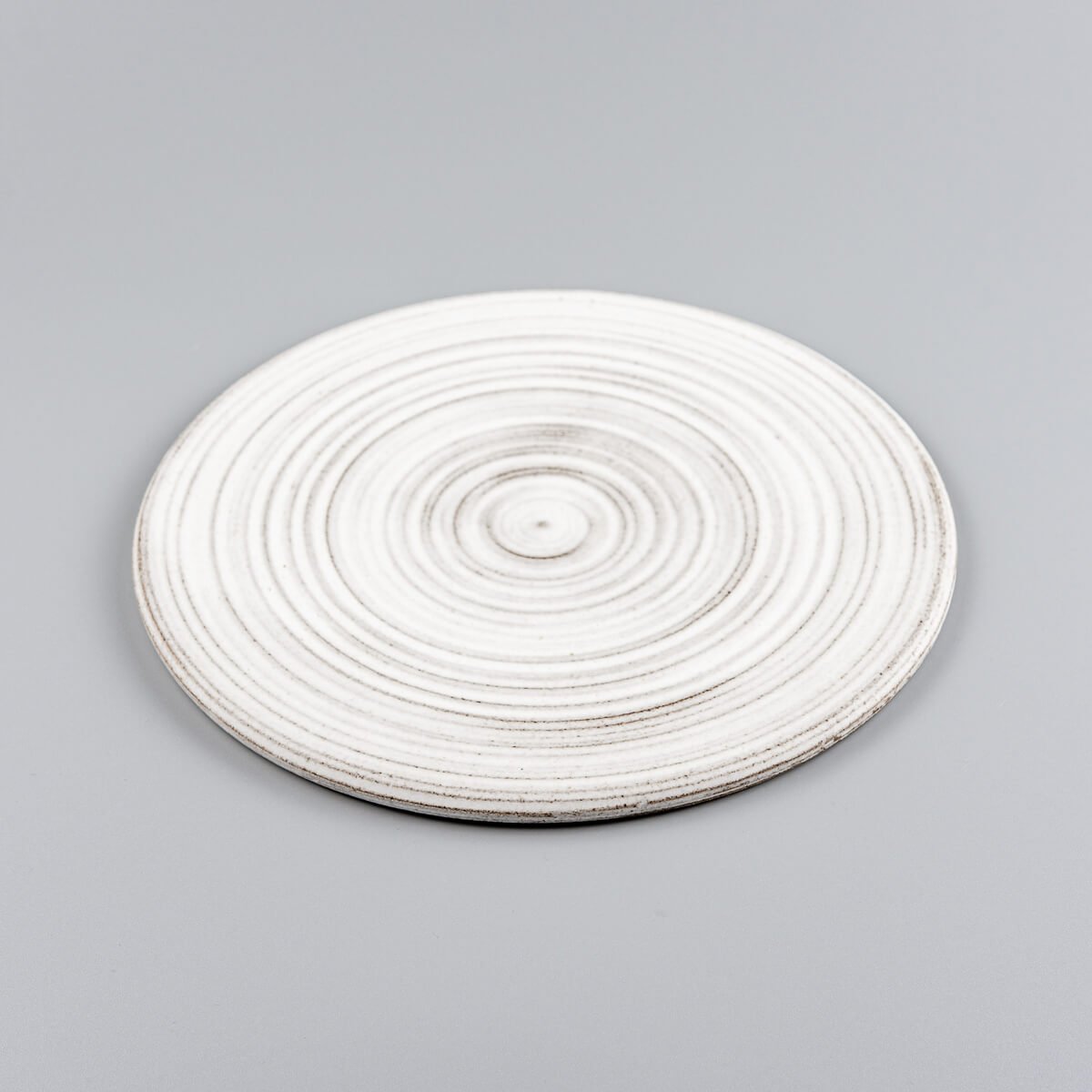Minimalist white ceramic plate handcrafted from stoneware clay for culinary plating.