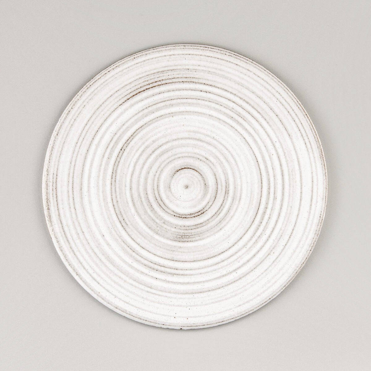 Flat handcrafted ceramic plate with matte white glaze and textured rings for fine dining restaurants.