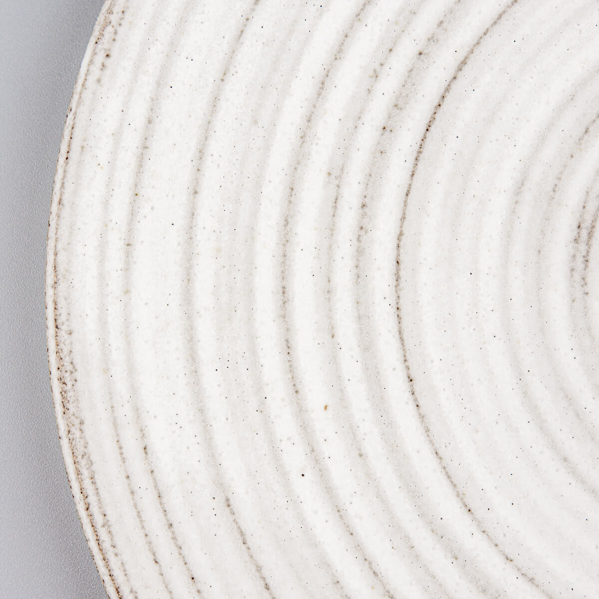 Detail of matte glaze finish and raw clay edges on handcrafted ceramic tableware.
