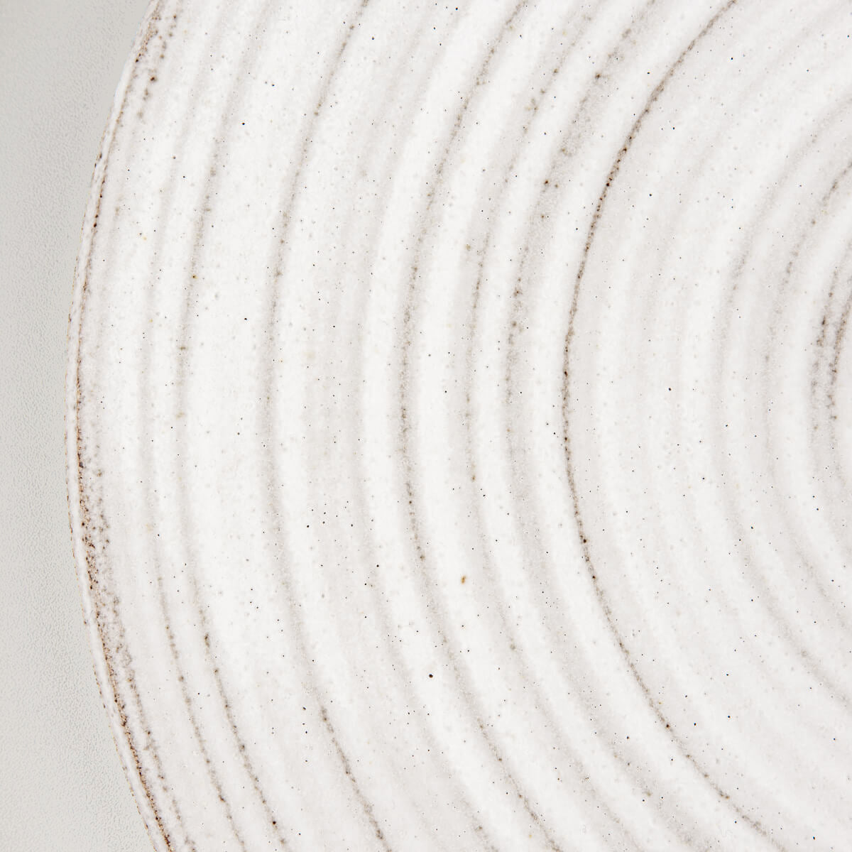 Detail of matte glaze finish and raw clay edges on handcrafted ceramic tableware.