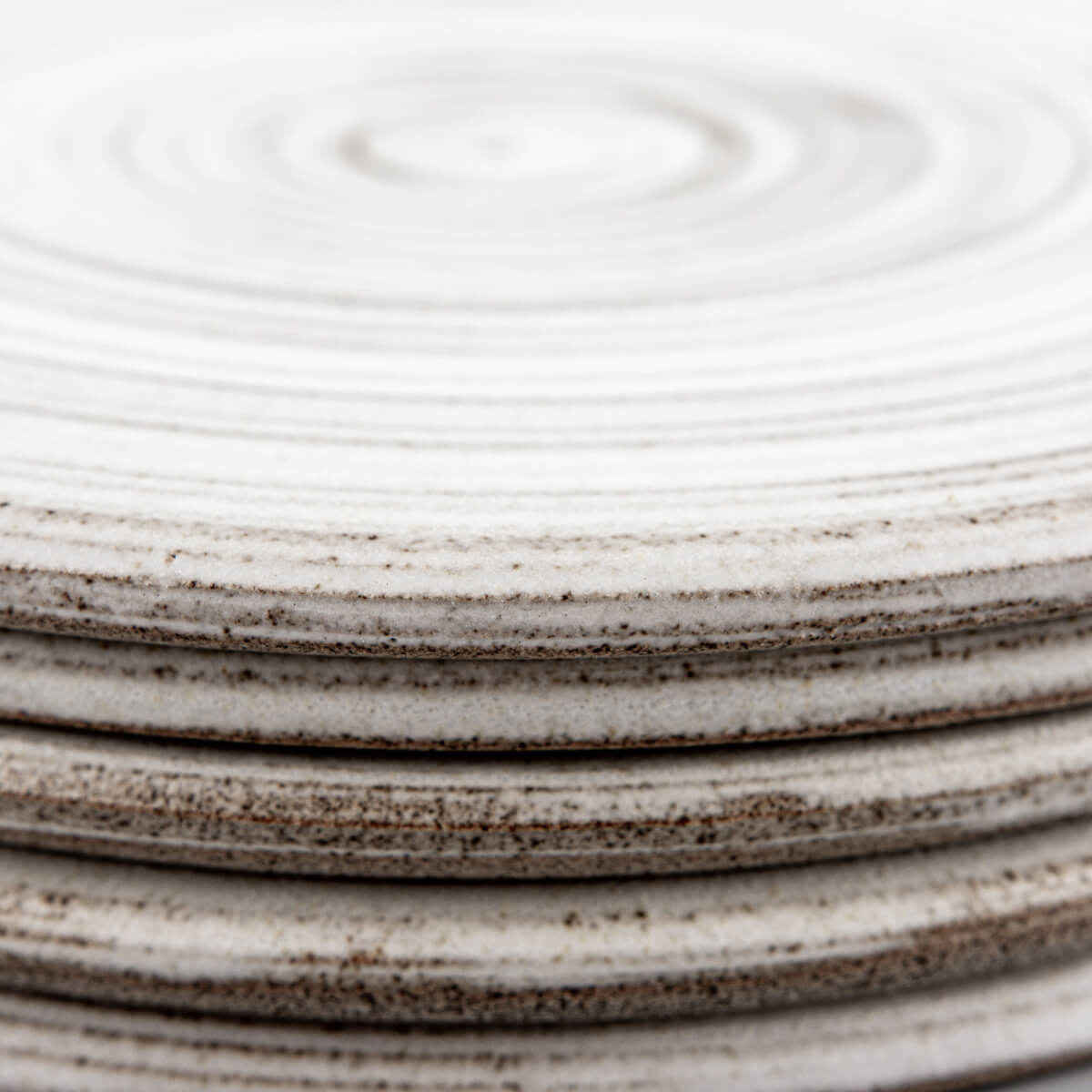 Stacked ceramic plates showing raw unglazed undersides and natural textures.