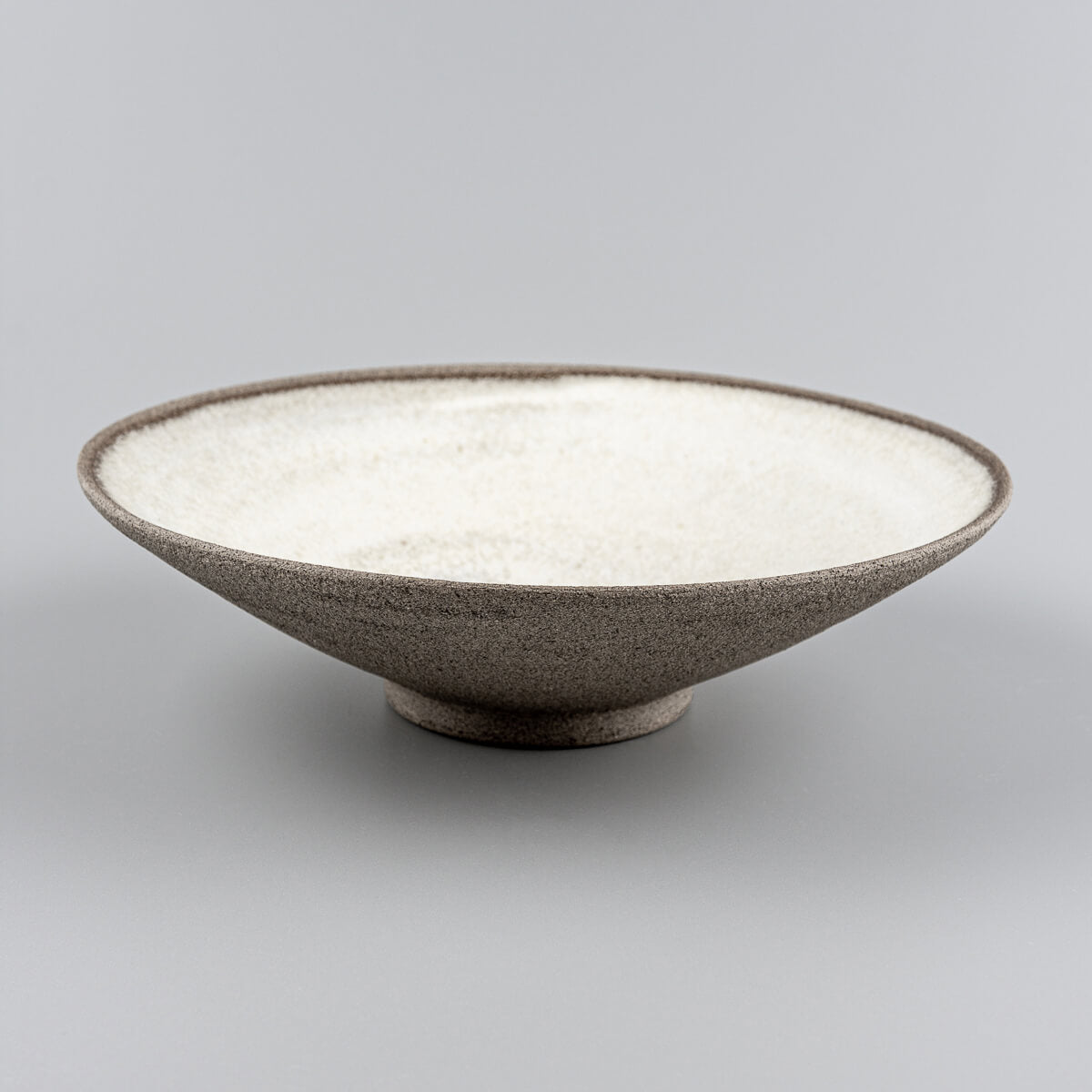 Handmade ceramic tableware held by hand, showcasing artisanal finish and fine dining use.