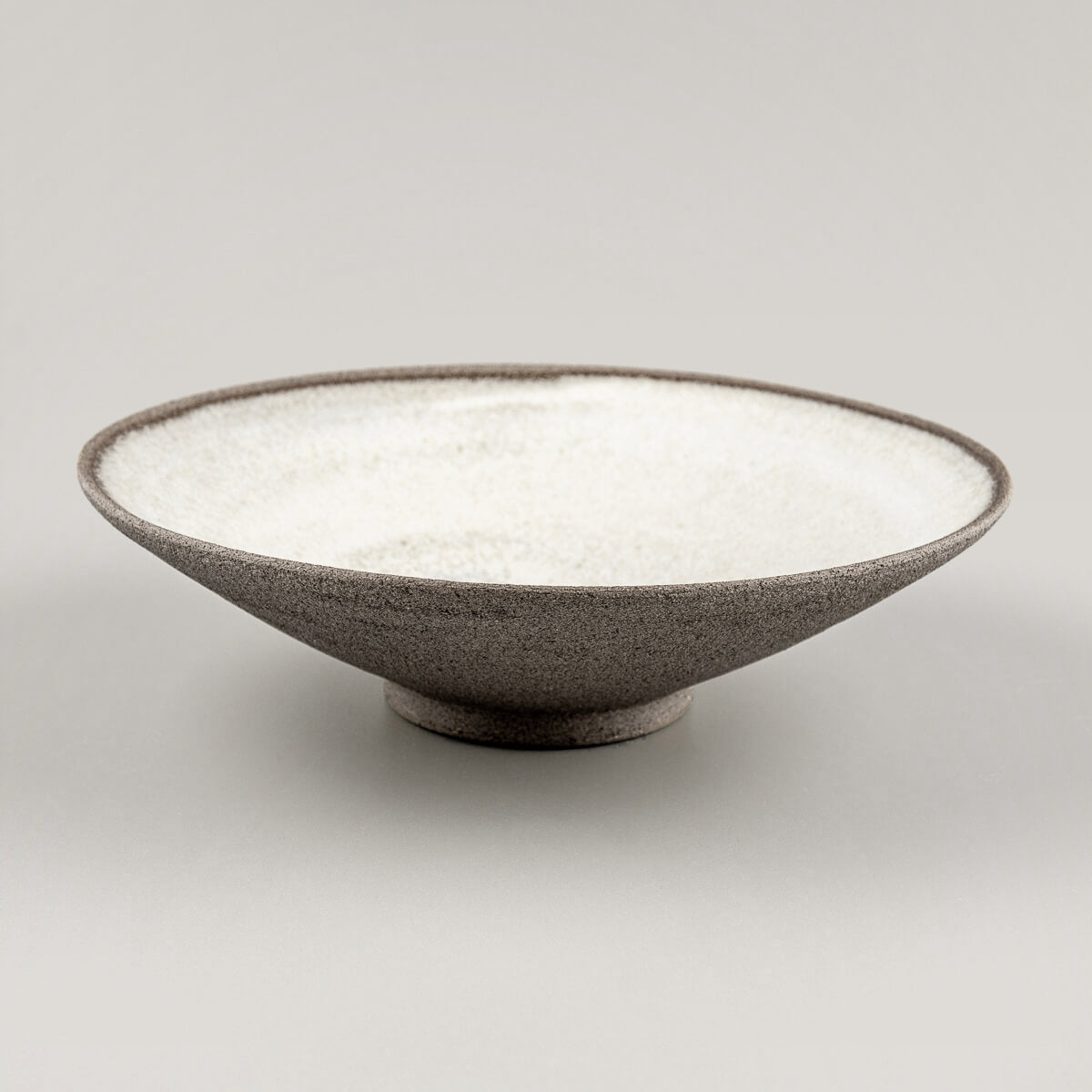 Handmade ceramic tableware held by hand, showcasing artisanal finish and fine dining use.