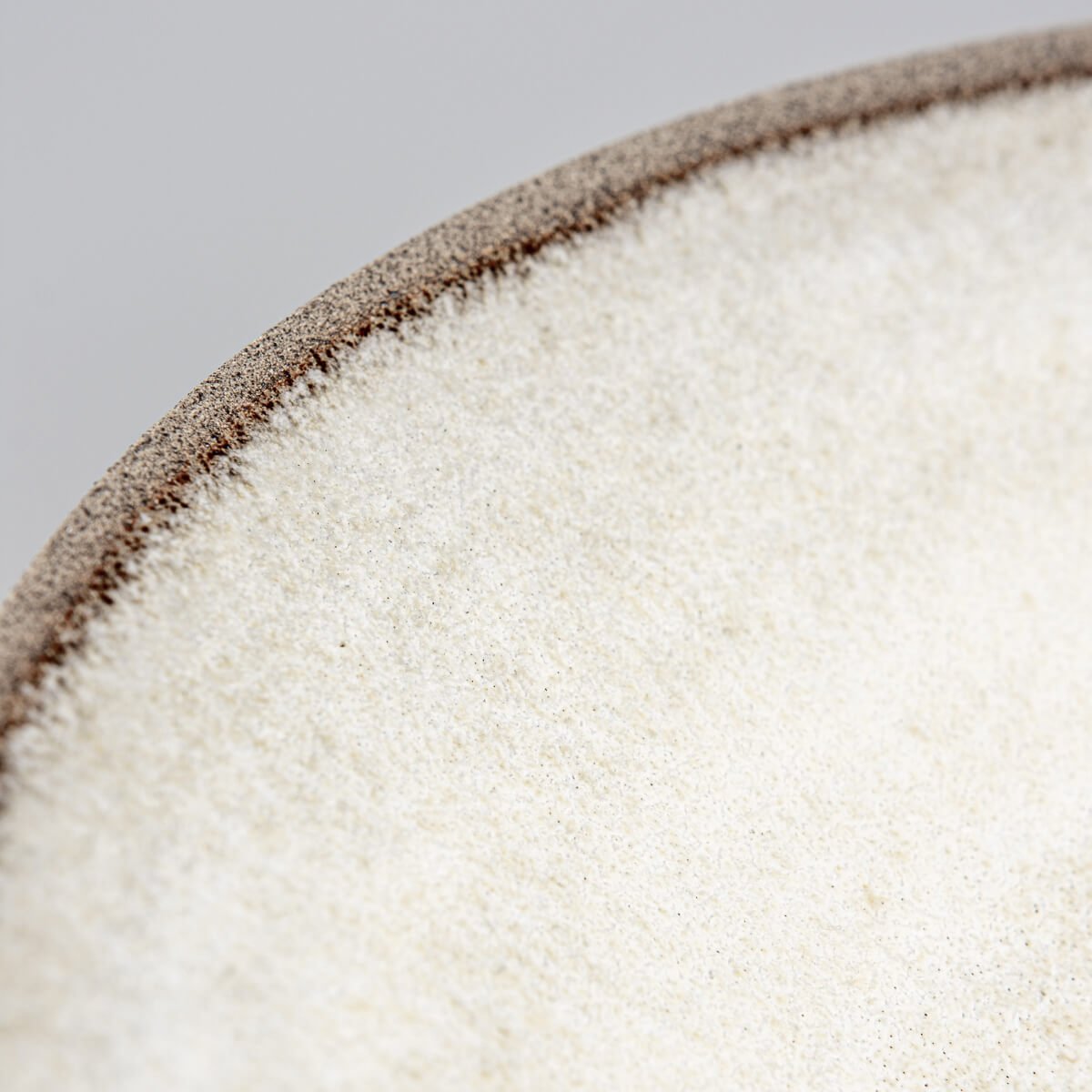 Artisan ceramic plate in stoneware with textured rim for sophisticated dining.