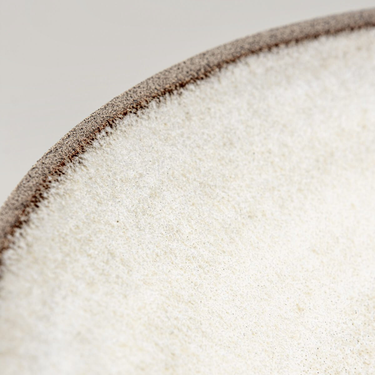 Artisan ceramic plate in stoneware with textured rim for sophisticated dining.