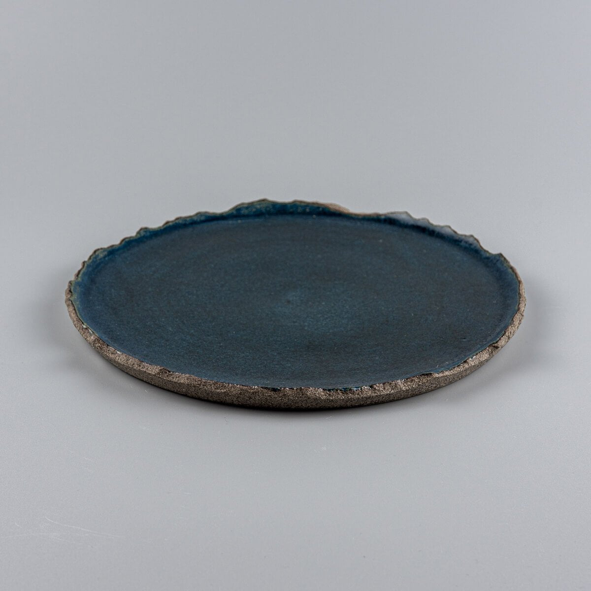 Side view of blue stoneware plate with organic rim, handcrafted for fine dining and interior styling.