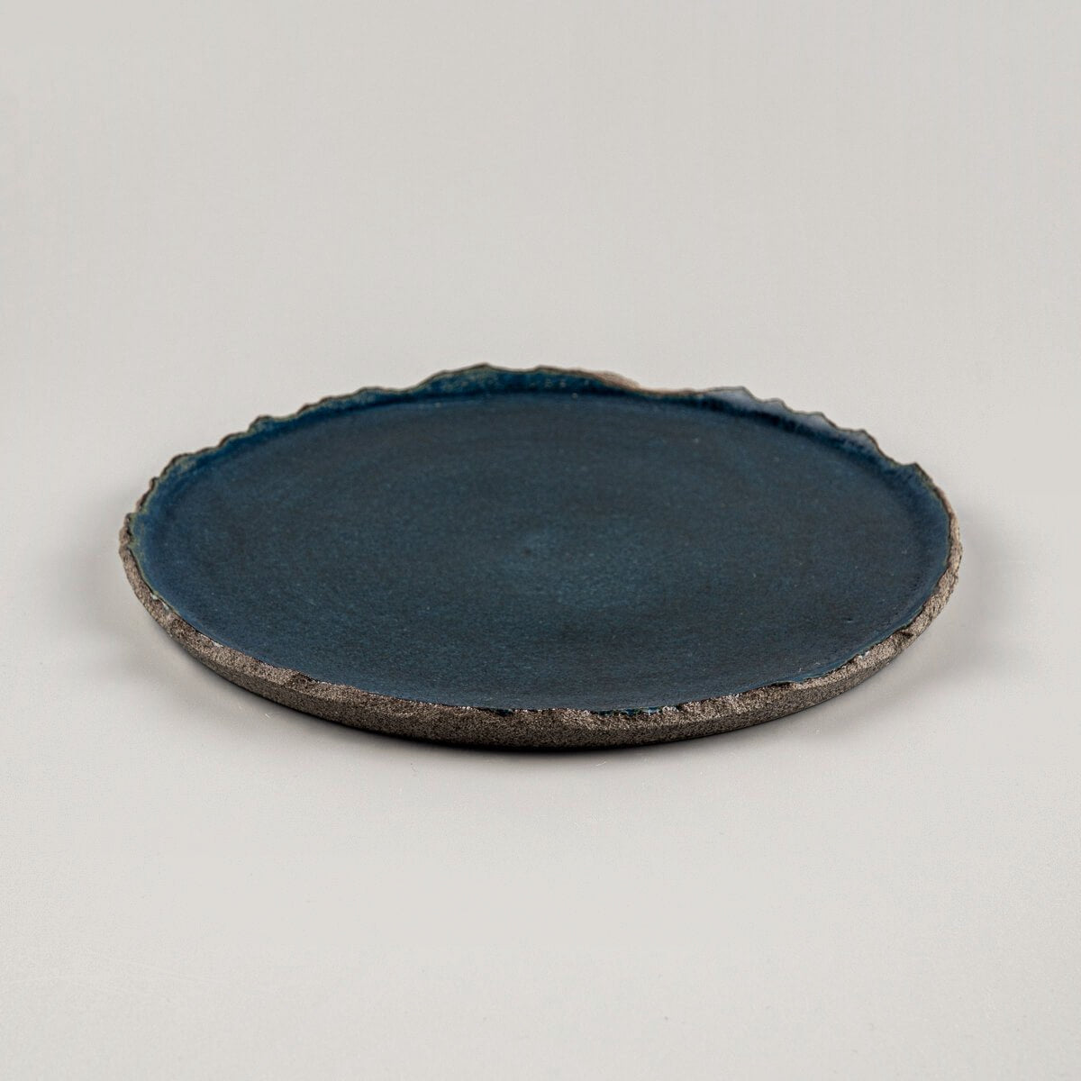 Side view of blue stoneware plate with organic rim, handcrafted for fine dining and interior styling.