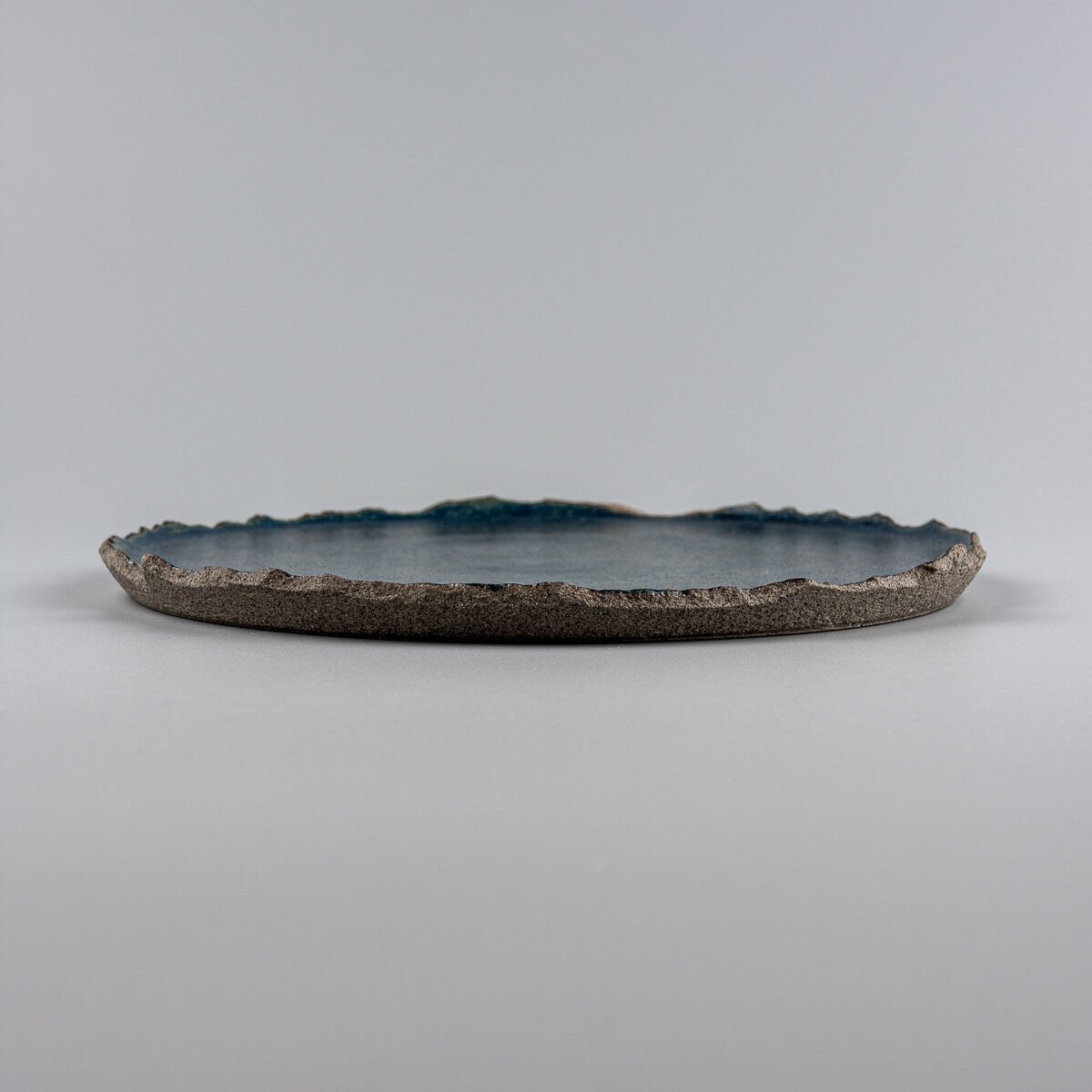 Profile of artisanal ceramic dessert plate showing unglazed textured base and flat glazed surface.
