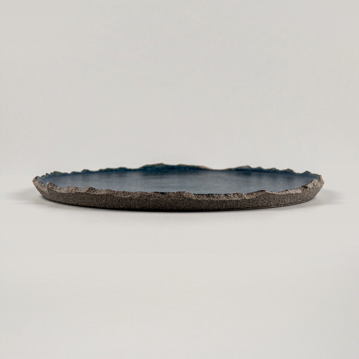 Profile of artisanal ceramic dessert plate showing unglazed textured base and flat glazed surface.
