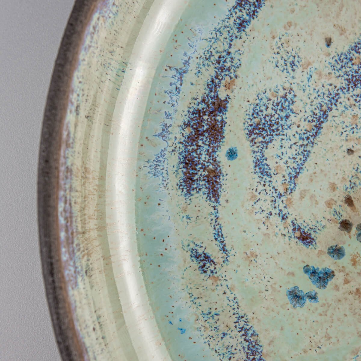 Close-up of glossy glaze texture with turquoise and blue artistic detailing.