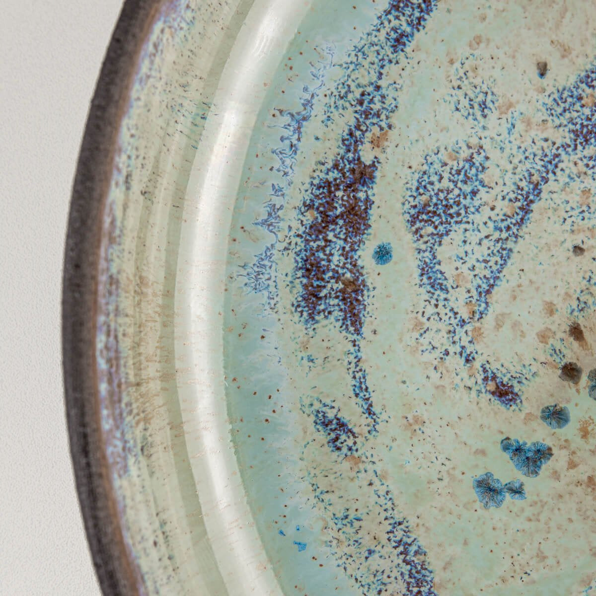 Close-up of glossy glaze texture with turquoise and blue artistic detailing.