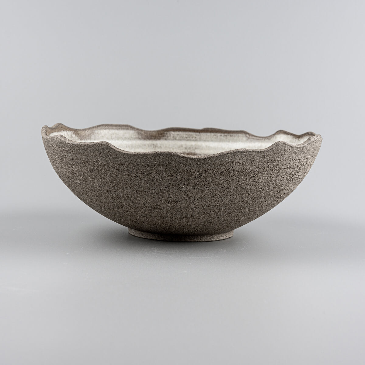Side profile of handmade ceramic bowl showing curved shape and unglazed natural clay surface.