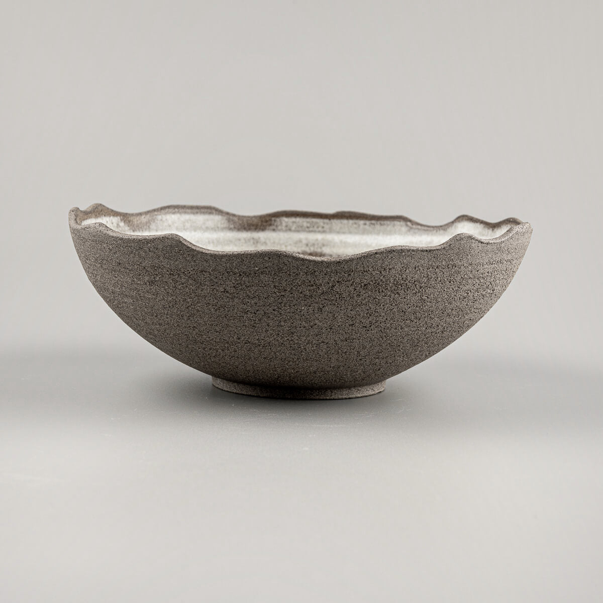 Side profile of handmade ceramic bowl showing curved shape and unglazed natural clay surface.