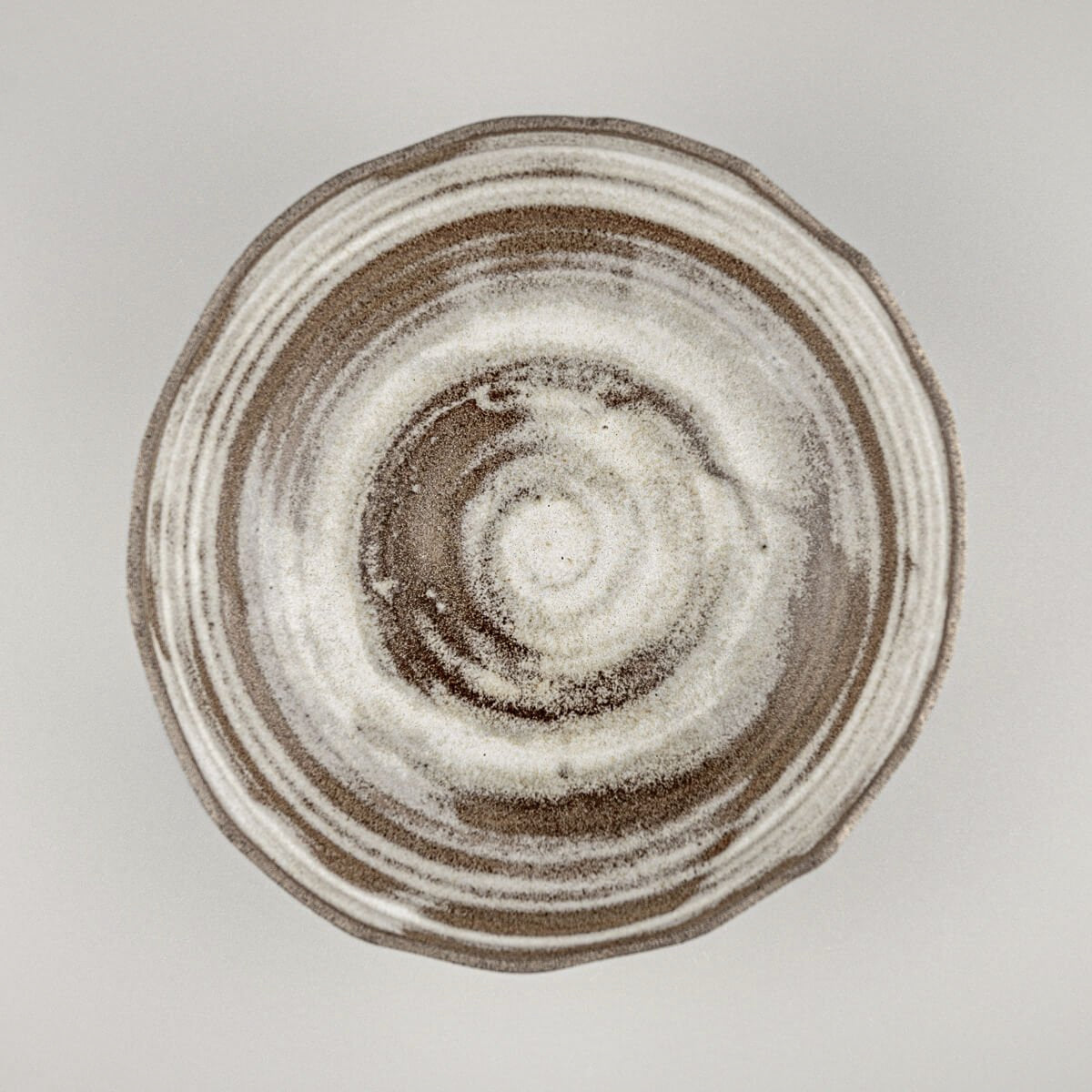 Top view of artisan stoneware bowl featuring swirling glaze pattern and handmade irregular rim.