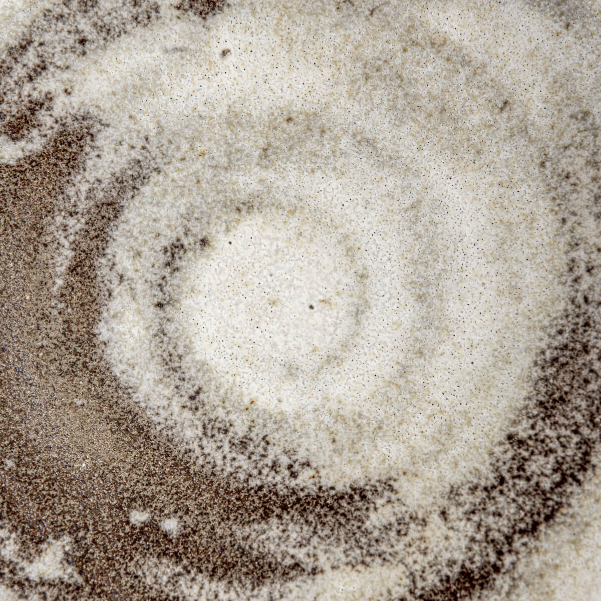 Interior swirl of handmade stoneware bowl with matte glaze and earthy color contrast.