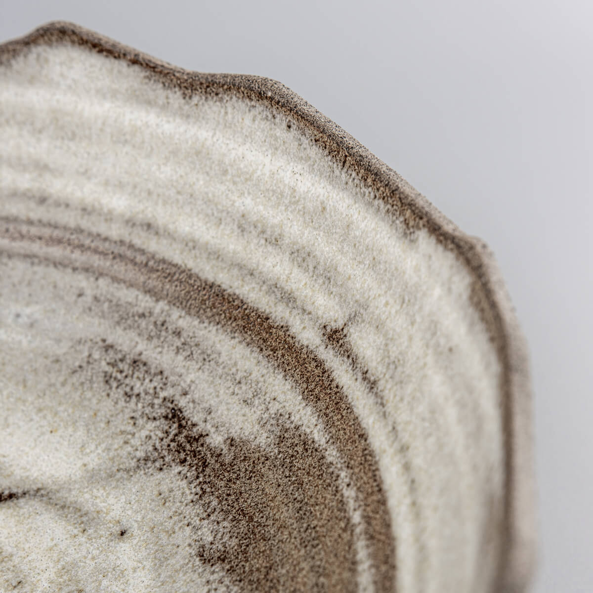 Detail view of uneven rim and layered glazing on artisanal ceramic serving bowl.