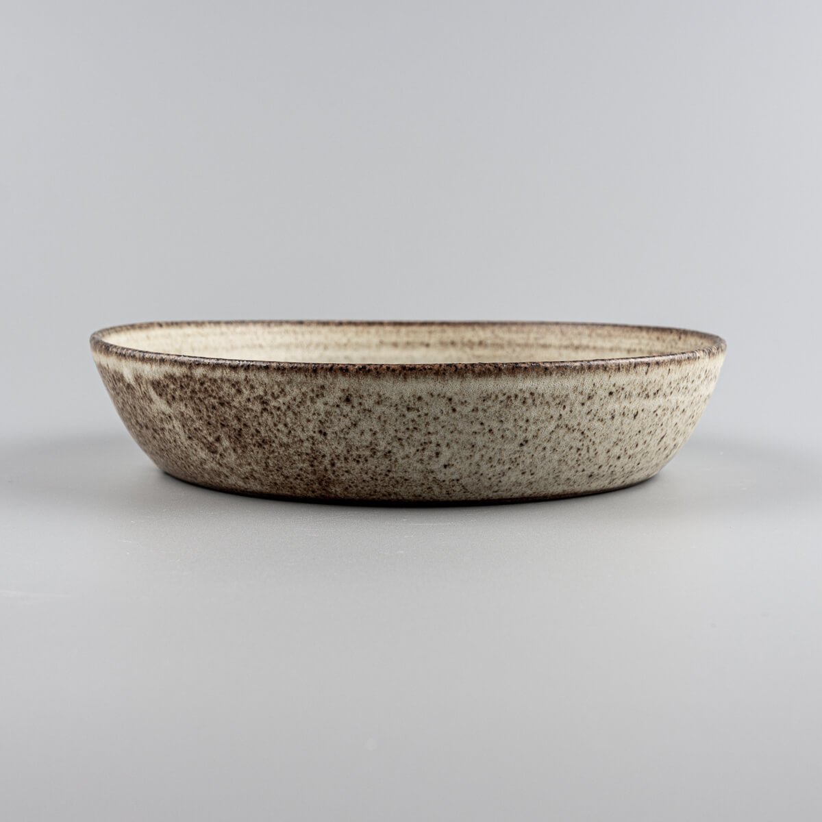 Rustic ceramic plate crafted from stoneware clay with natural texture and handmade finish.