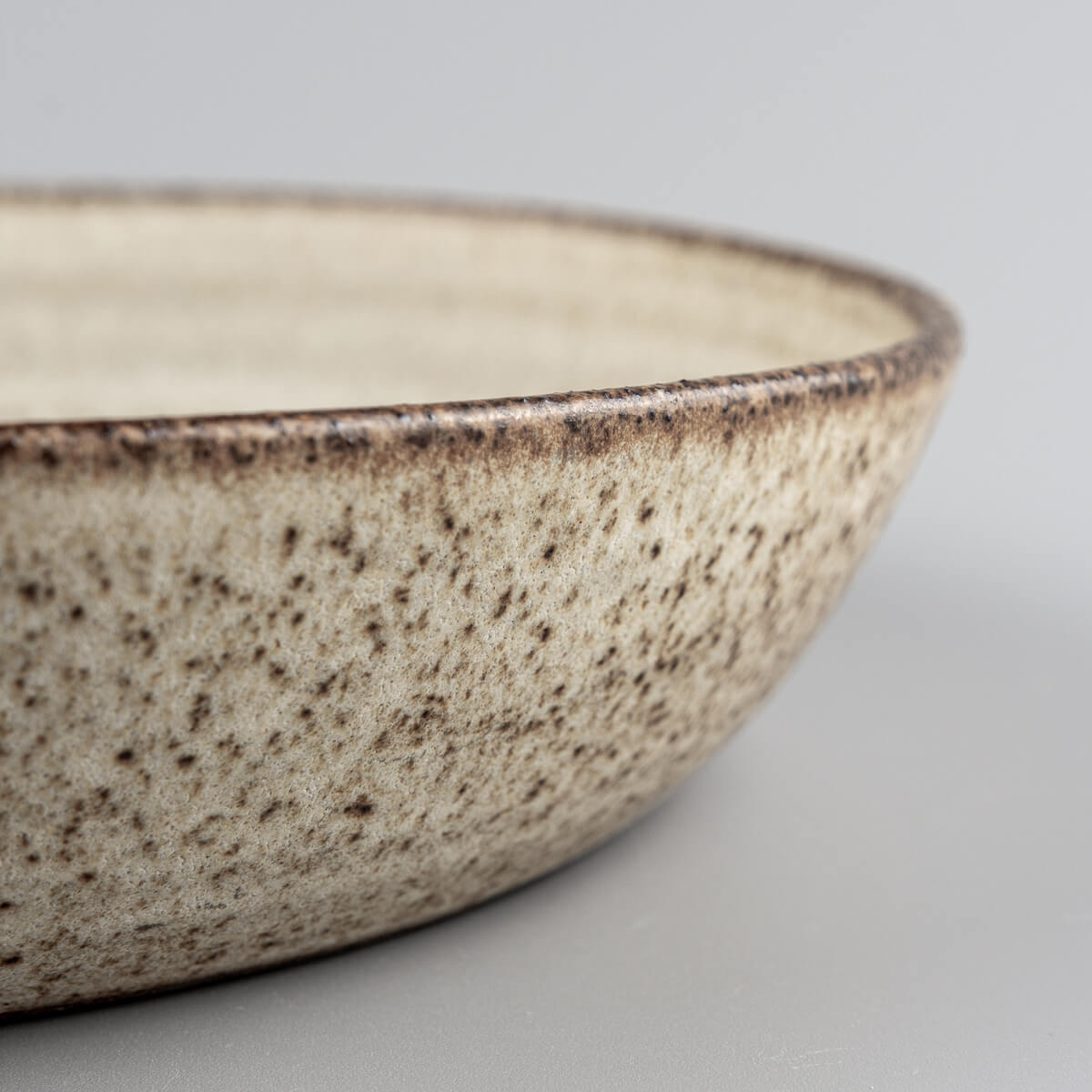 Hand-thrown ceramic plate with rustic aesthetic and unglazed outer base for contrast.