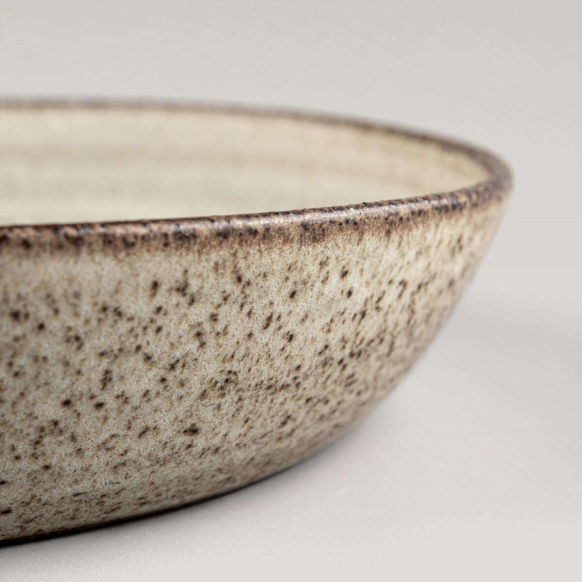 Hand-thrown ceramic plate with rustic aesthetic and unglazed outer base for contrast.
