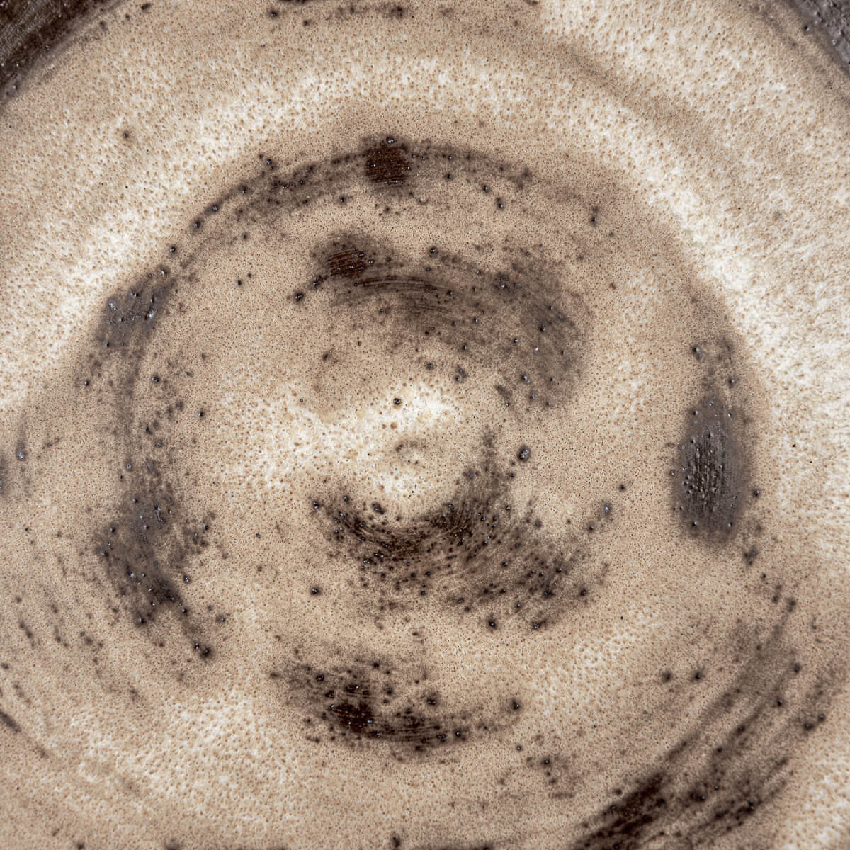 Handmade ceramic plate with spiral glaze and raw stoneware bottom for artistic interiors.