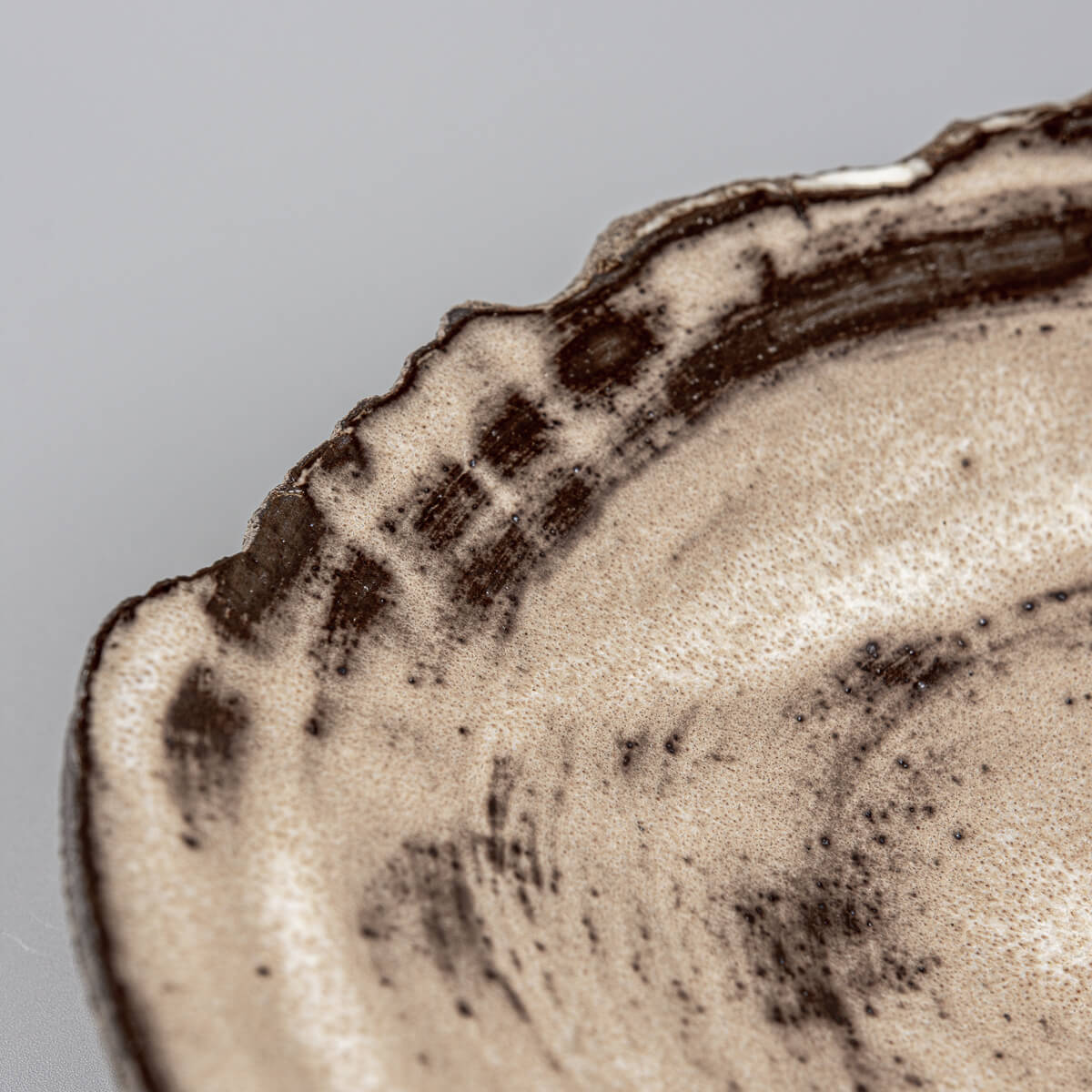 Detailed profile of handcrafted ceramic plate with chipped edge design.