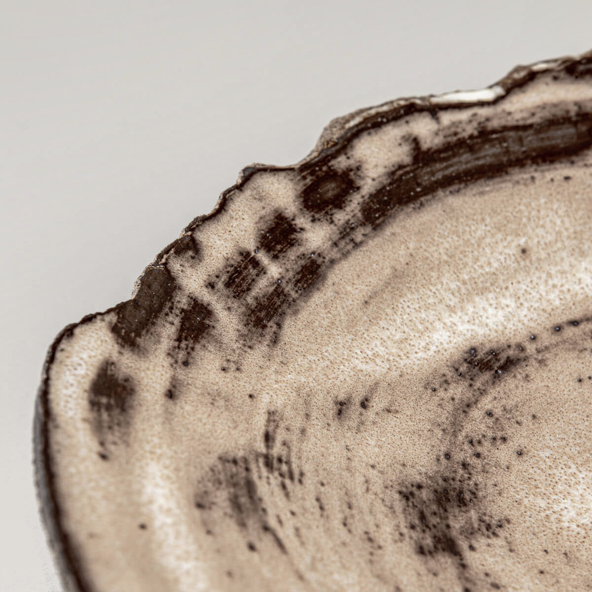 Detailed profile of handcrafted ceramic plate with chipped edge design.
