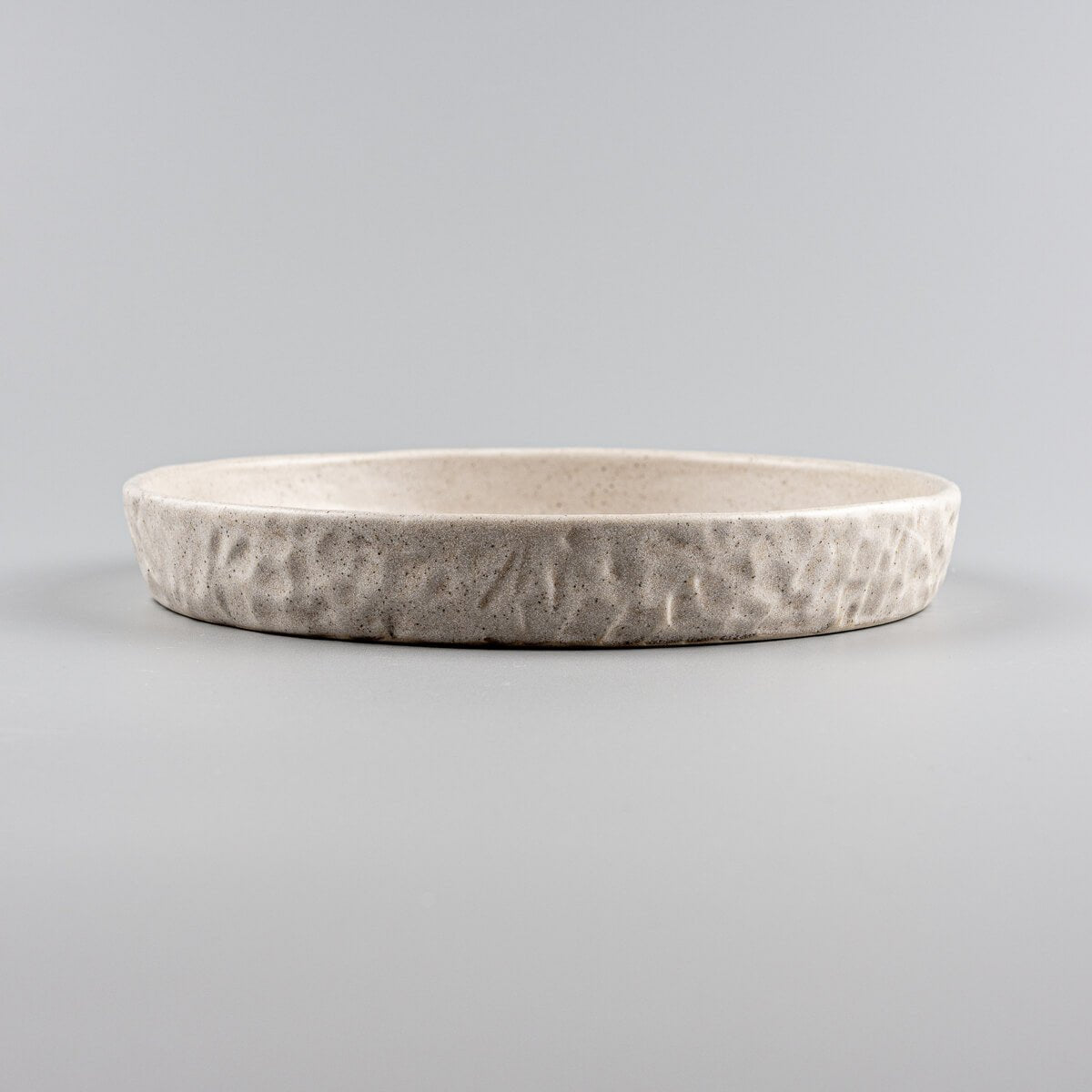 Fine dining stoneware plate in beige, handmade for elegant dessert serving.