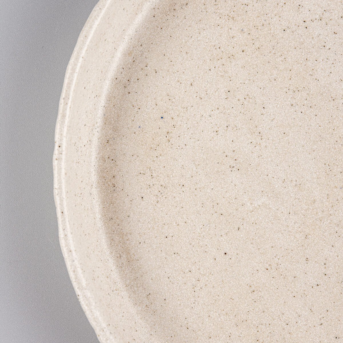 Minimalist handcrafted ceramic plate with flat bottom and curved edges.