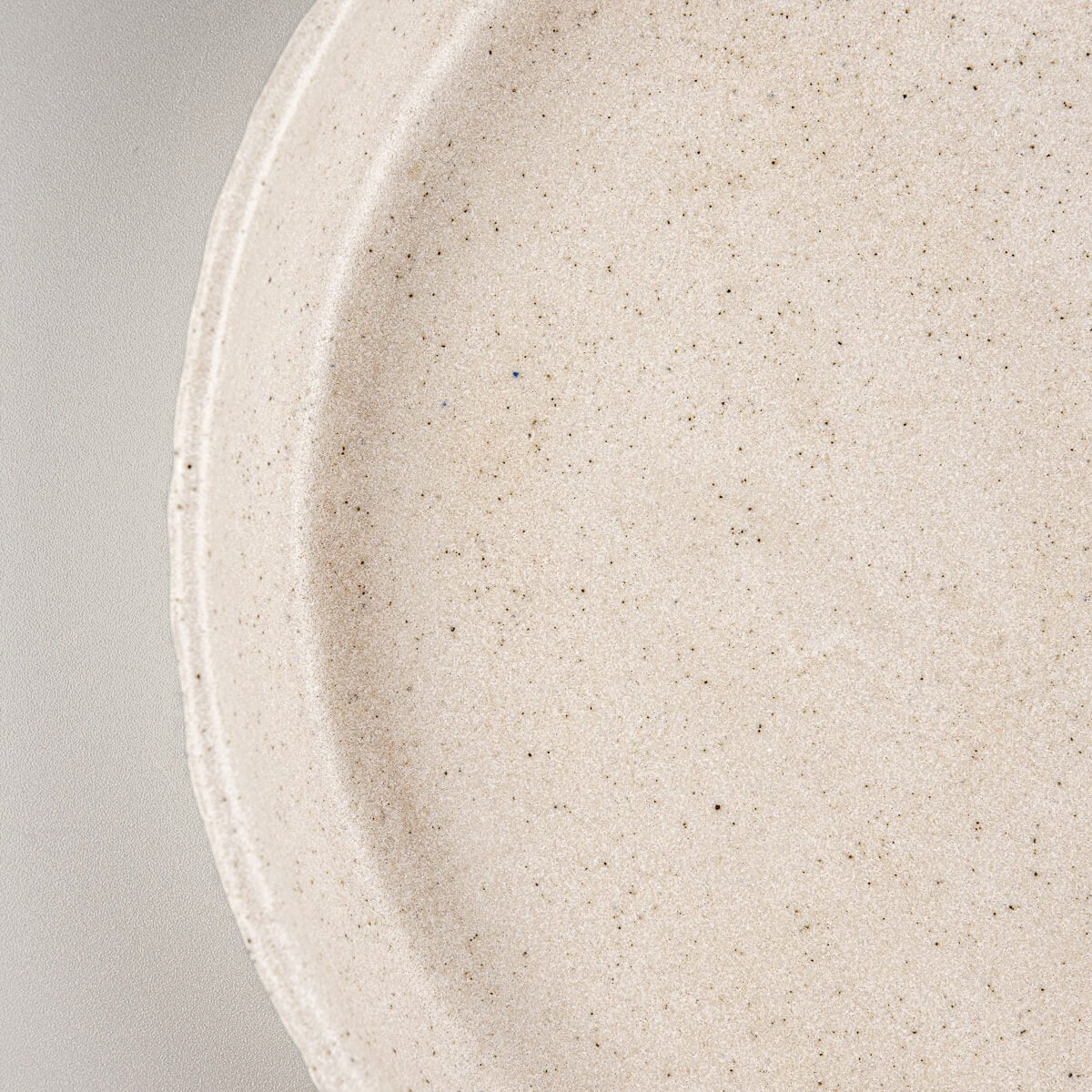Minimalist handcrafted ceramic plate with flat bottom and curved edges.