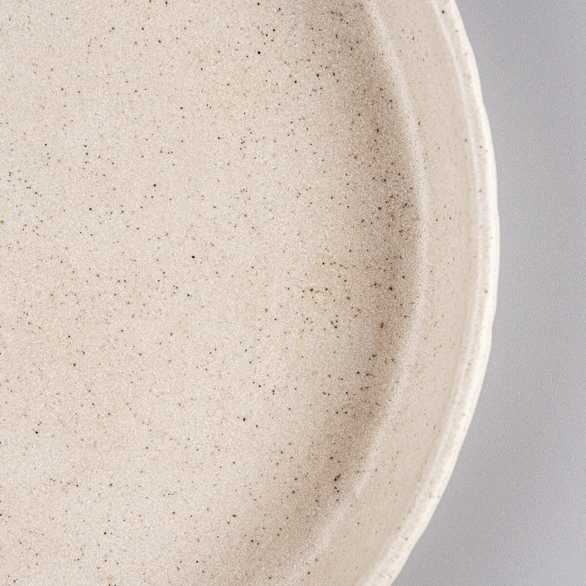 Stone-textured rim detail on handmade coupe-deep ceramic plate.