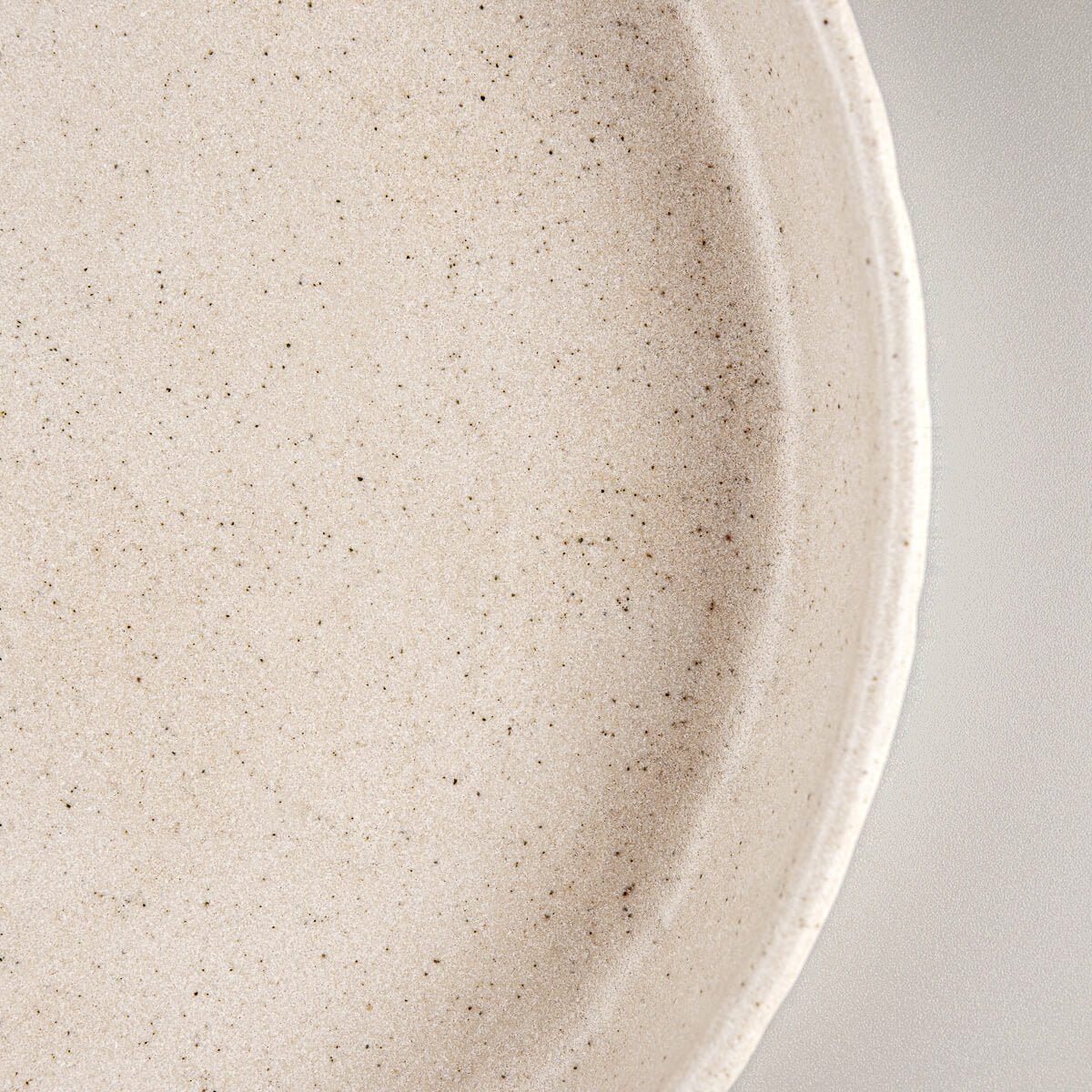 Stone-textured rim detail on handmade coupe-deep ceramic plate.