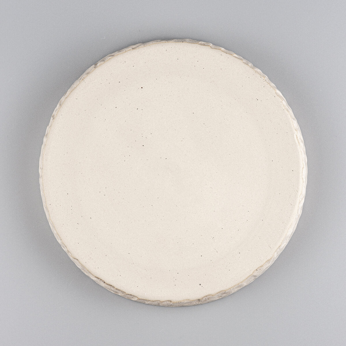Underside of artisan stoneware plate showing unglazed natural beige base.
