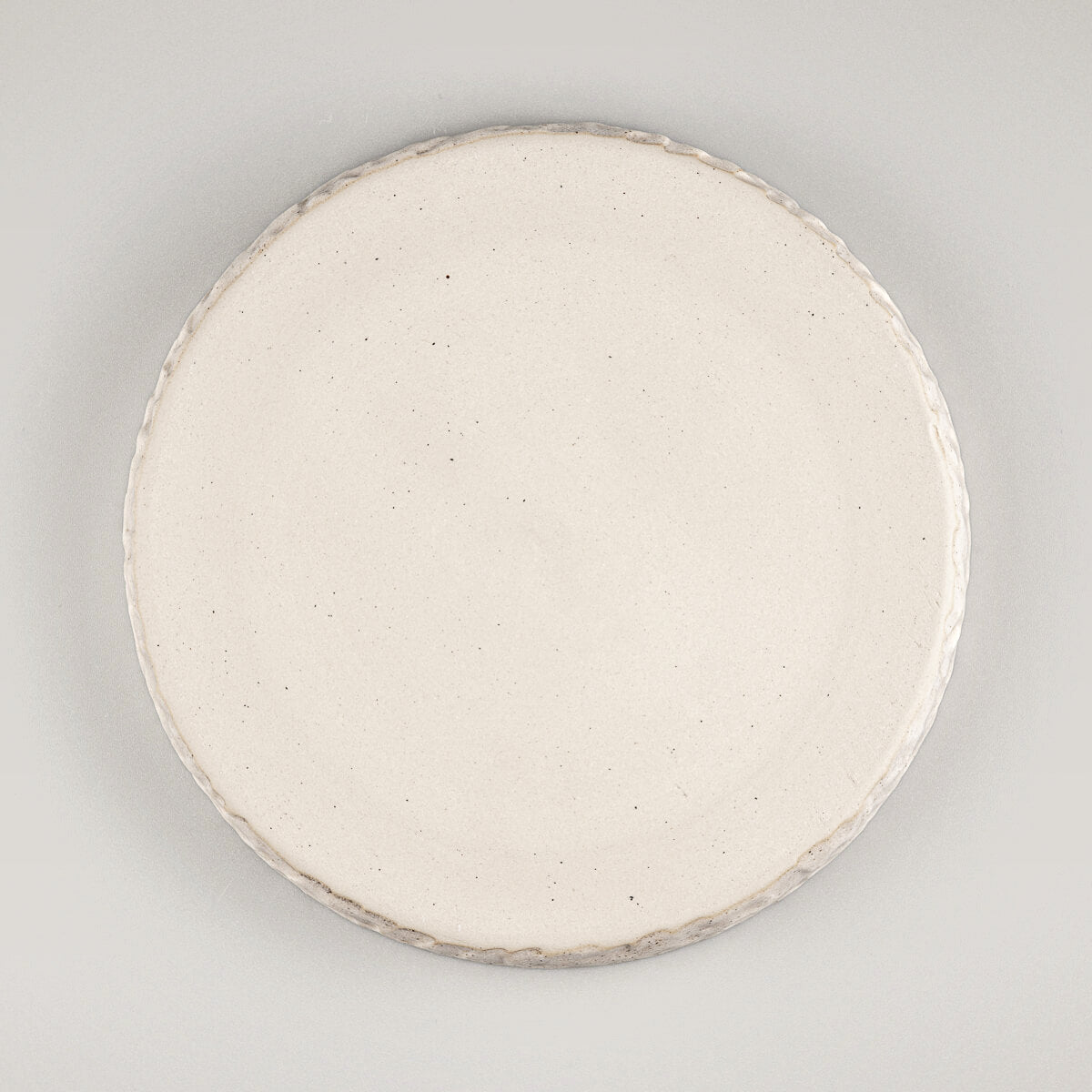 Underside of artisan stoneware plate showing unglazed natural beige base.