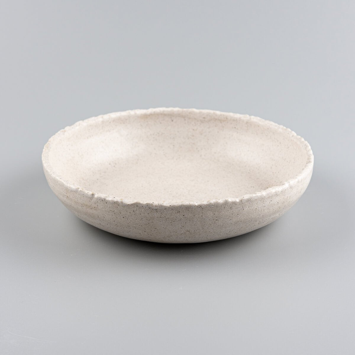 Side profile of handcrafted stoneware dinner plate with deep coupe form for upscale restaurant plating.