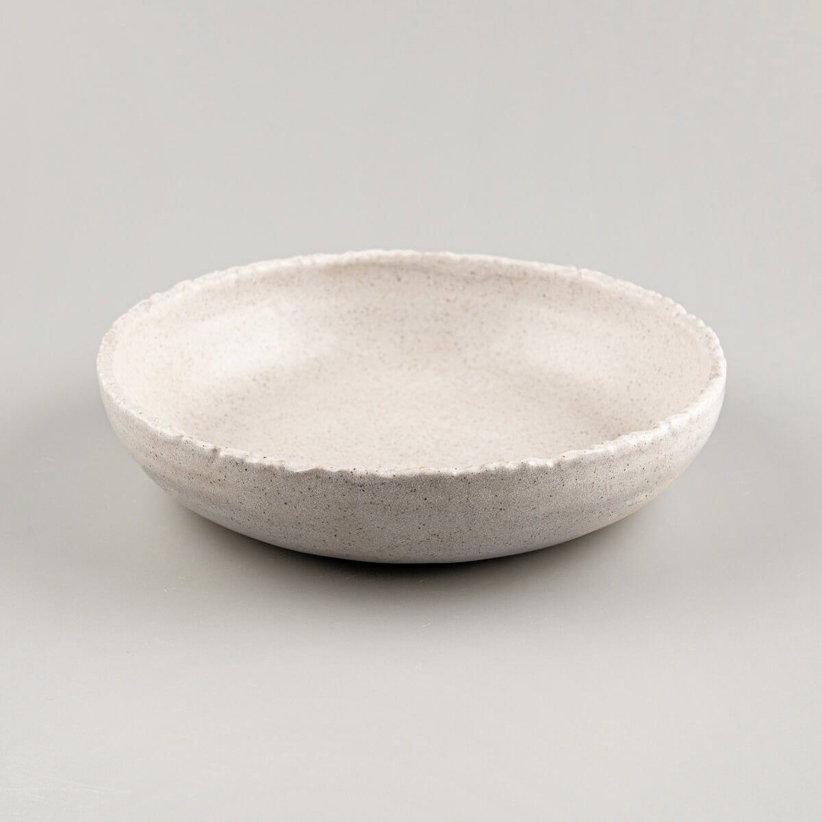 Side profile of handcrafted stoneware dinner plate with deep coupe form for upscale restaurant plating.