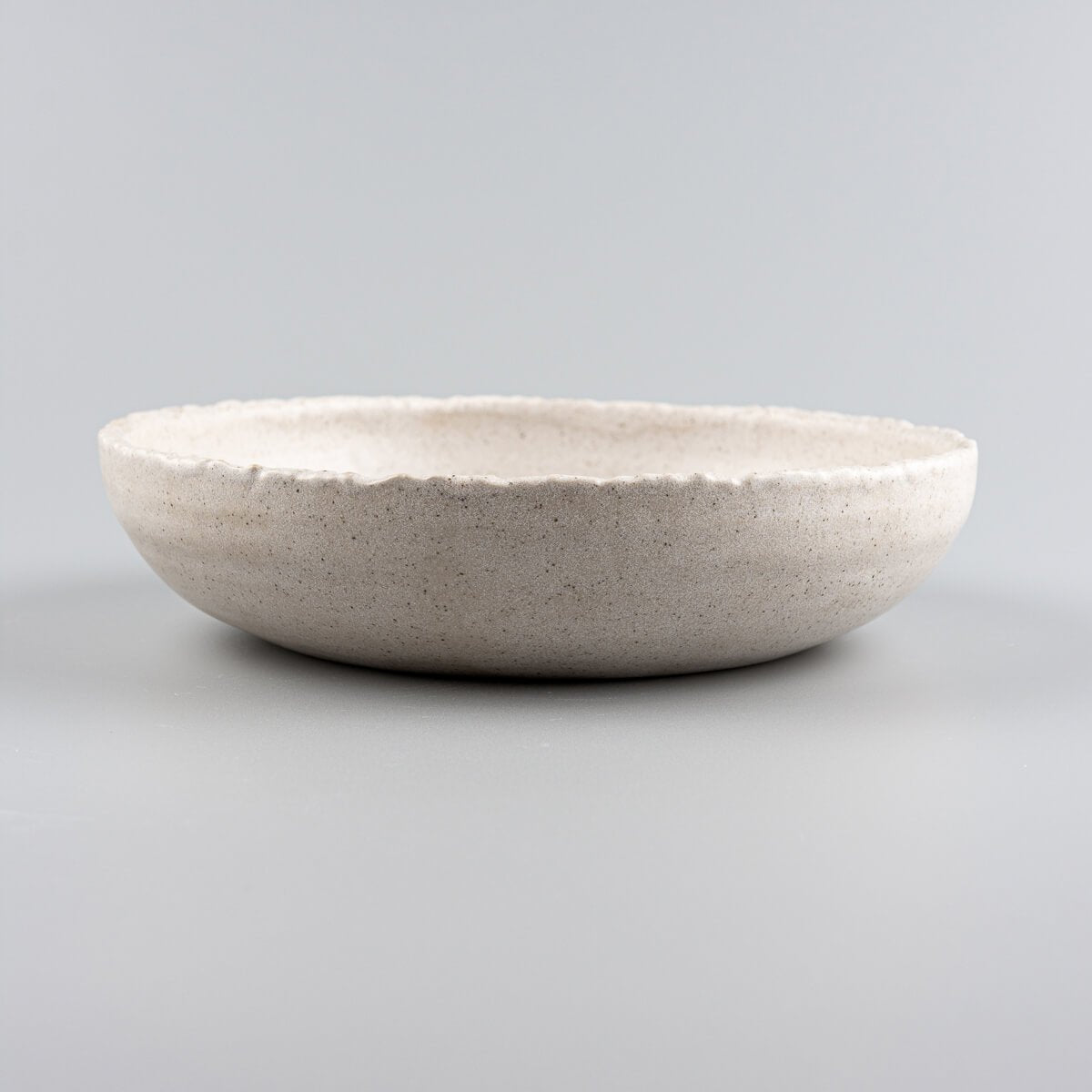 Elevated view of luxury handmade dinner plate in stone-textured glaze, perfect for boutique hotel tableware.