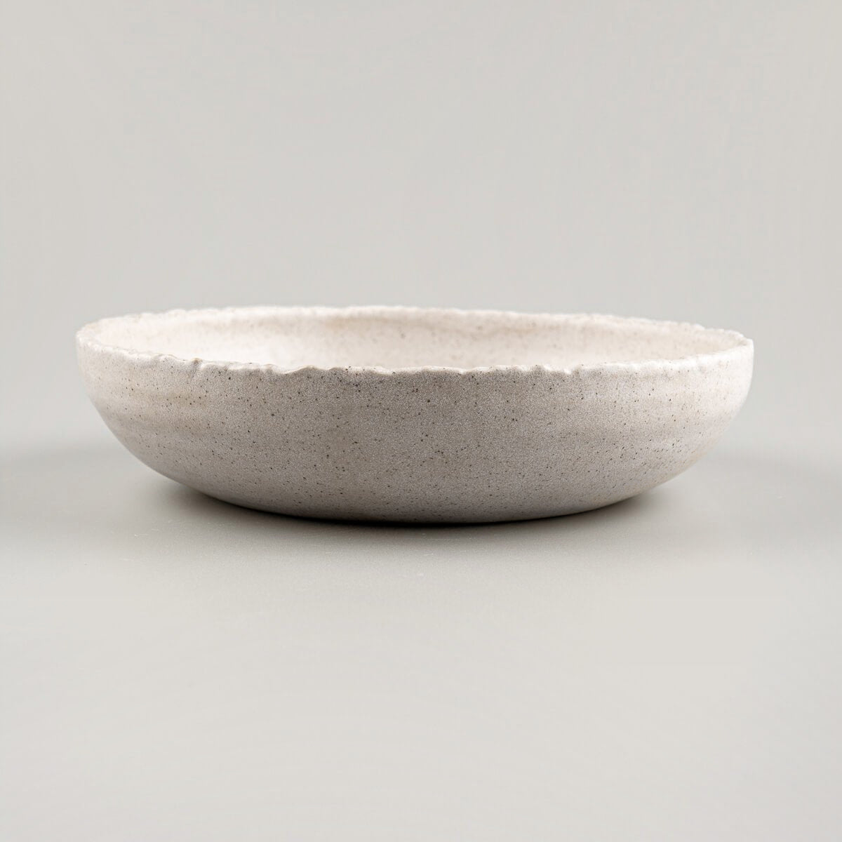 Elevated view of luxury handmade dinner plate in stone-textured glaze, perfect for boutique hotel tableware.