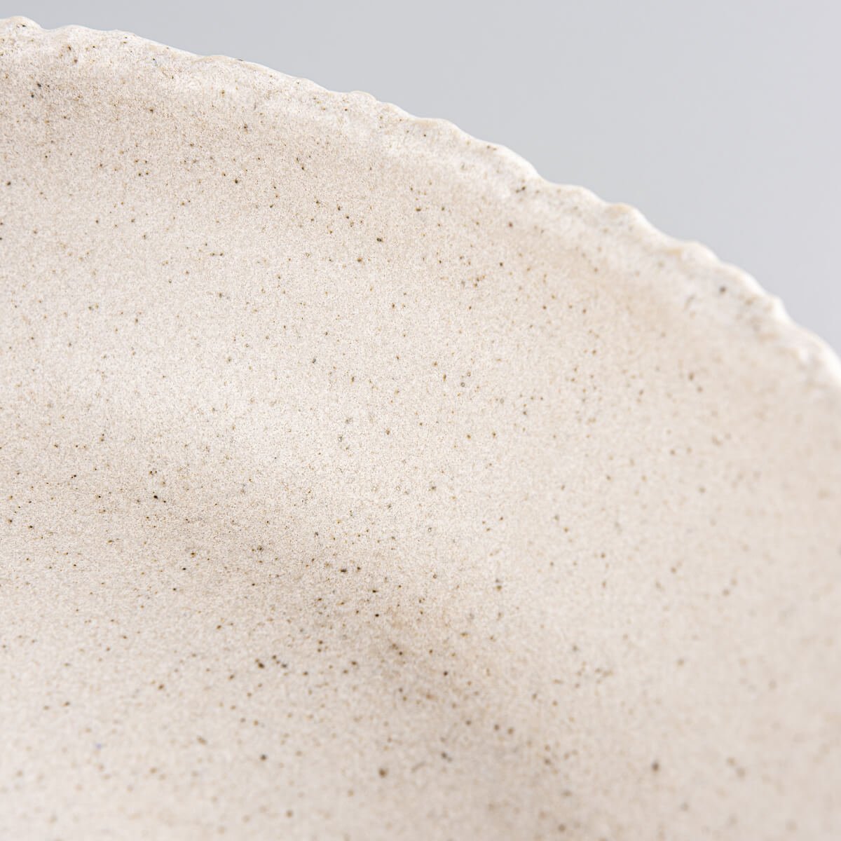 Interior curve and glaze of stoneware dinner plate designed for food presentation in elegant settings.