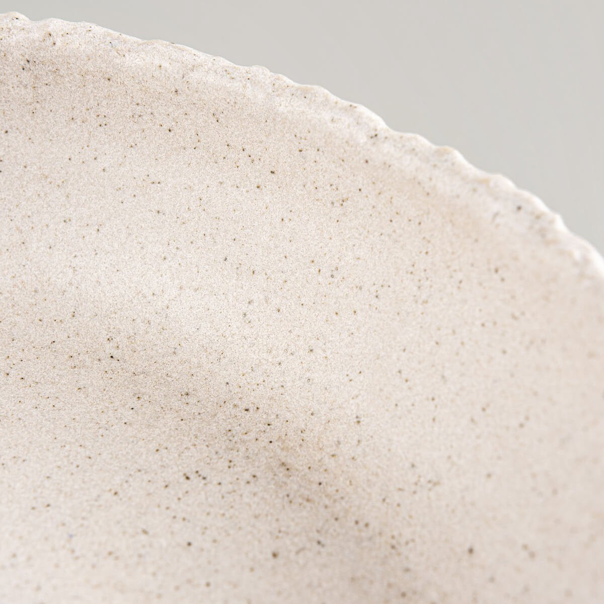 Interior curve and glaze of stoneware dinner plate designed for food presentation in elegant settings.