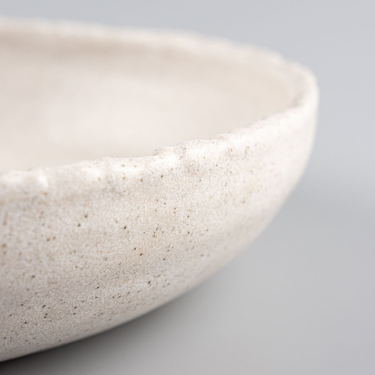 Detail of rustic hand-carved stoneware edge highlighting artisanal craftsmanship and premium quality.