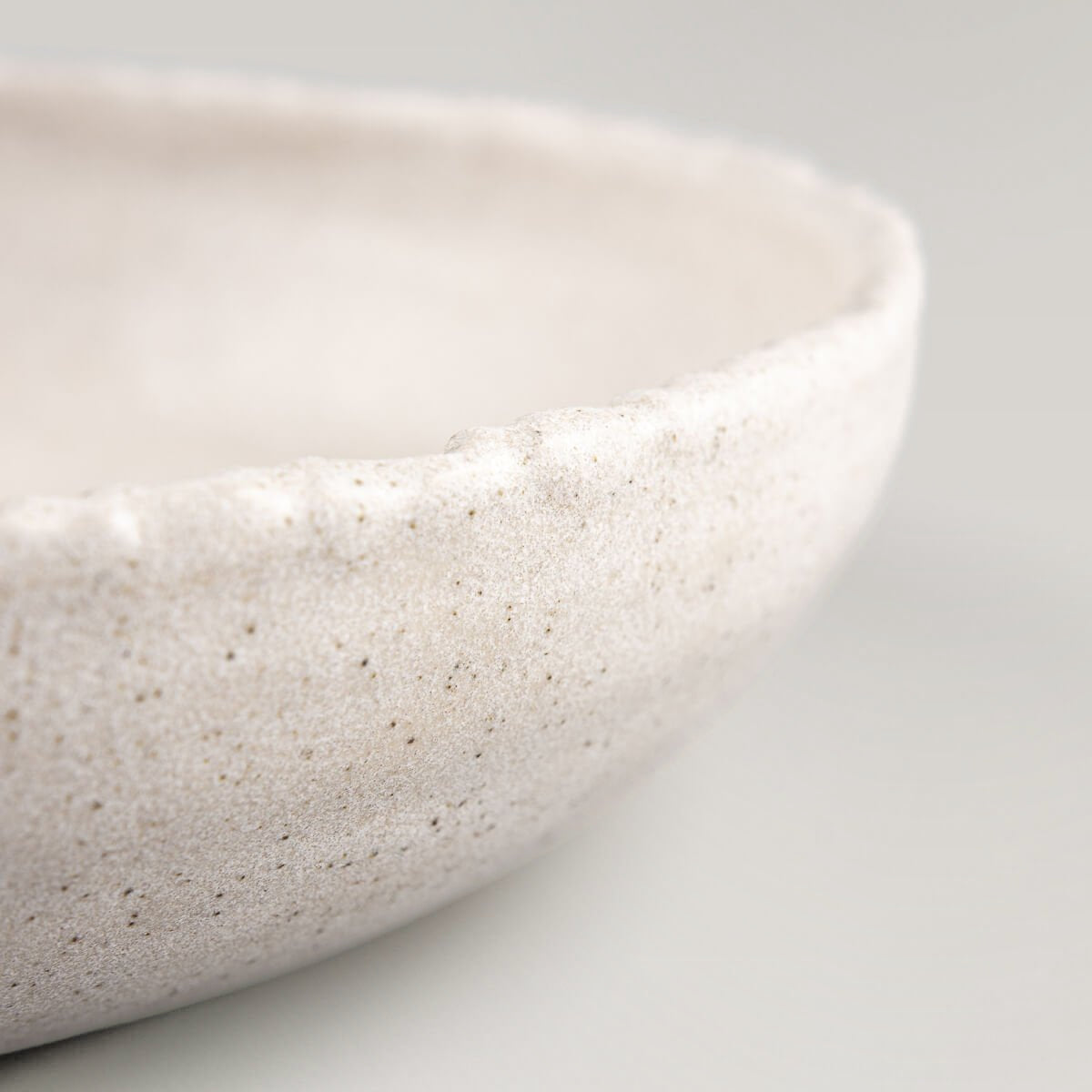 Detail of rustic hand-carved stoneware edge highlighting artisanal craftsmanship and premium quality.