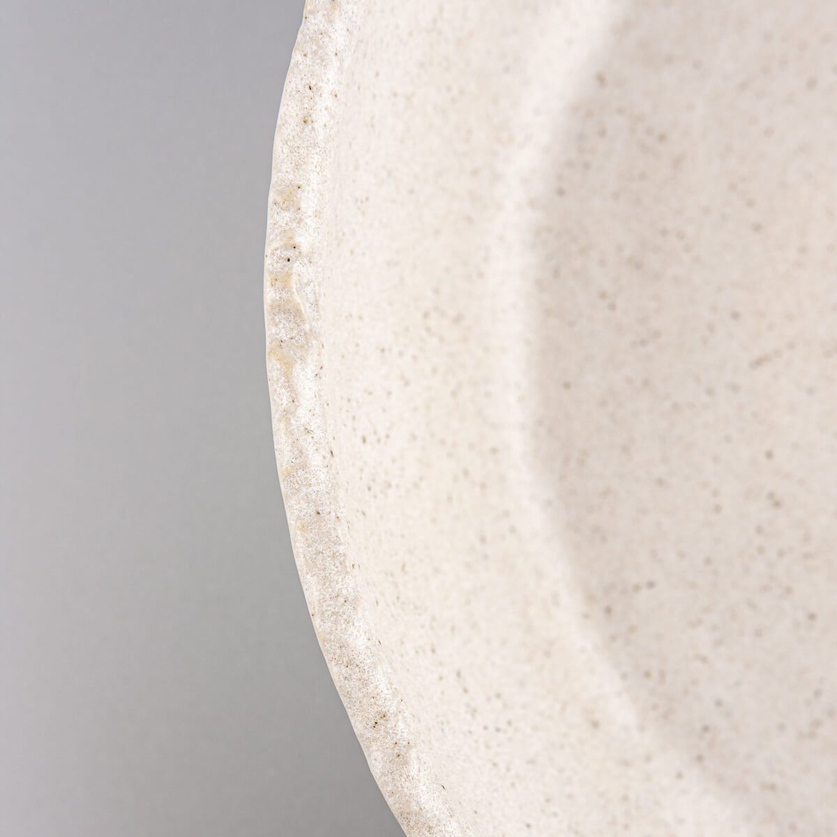 Fine handcrafted details on rim and surface of stoneware plate for luxury culinary serving.