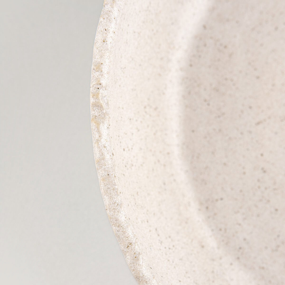Fine handcrafted details on rim and surface of stoneware plate for luxury culinary serving.
