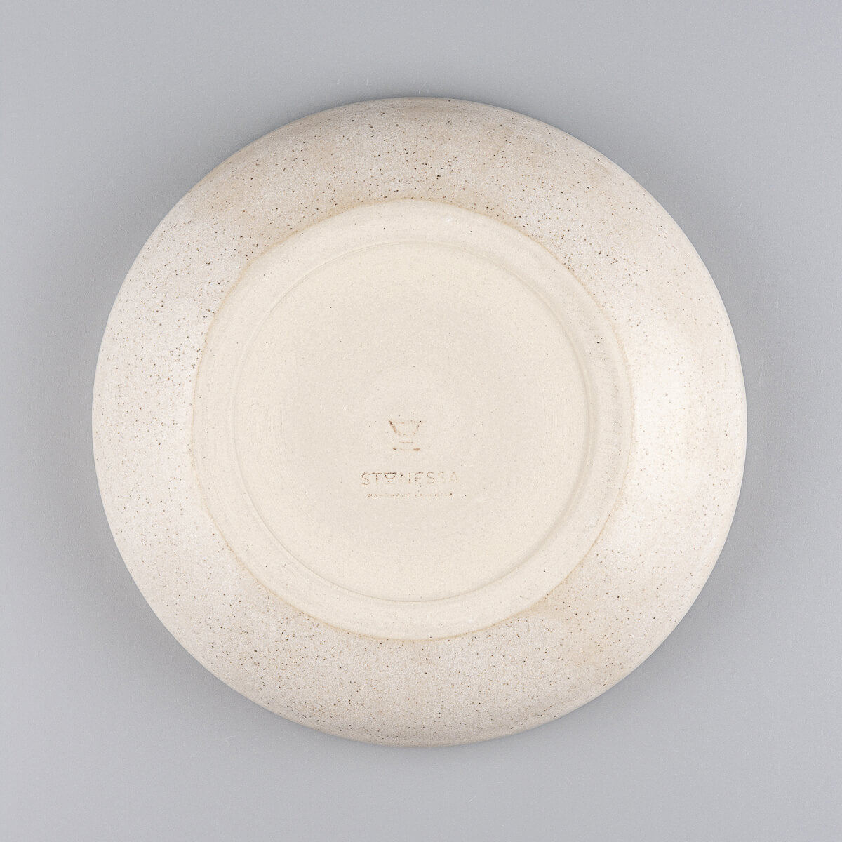 Top-down view of round ceramic dinner plate with minimalist design and handmade charm.